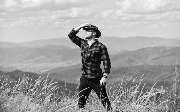 Inspiratie zoeken man op berglandschap kamperen en wandelen platteland concept boer op rancho reizen avontuur hipster sexy macho man in geruit hemd cowboy in hoed buiten