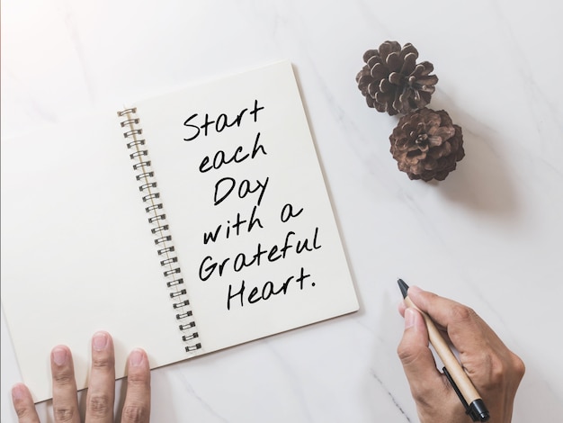 Inspirational motivating quote on notebook with pine cone and hands writing