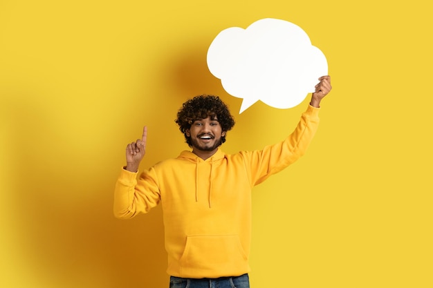 Inspired eastern guy holding speech bubble and showing eureka gesture