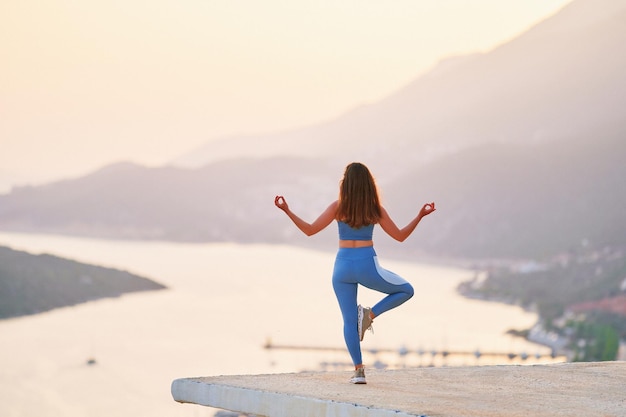 Donna ispirata che gode della meditazione in cima con una splendida vista al tramonto. sollievo dallo stress e pulisci le menti sane