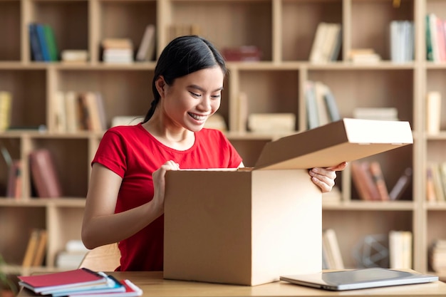 Inspired happy young asian female opens cardboard box enjoy online shopping and huge sale