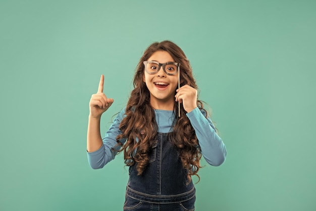 inspired with idea amazed funny child with glasses teen partygoer party time birthday holiday celebration having fun lets celebrate kid with long curly hair on blue background