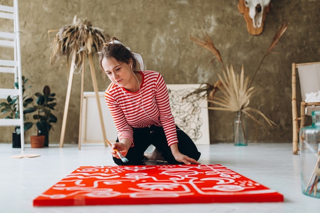 Photo inspired young artist listening music in headphones and painting on easel