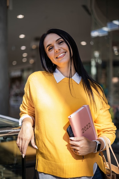 Inspired young business woman with a smile and holding coral colored diary