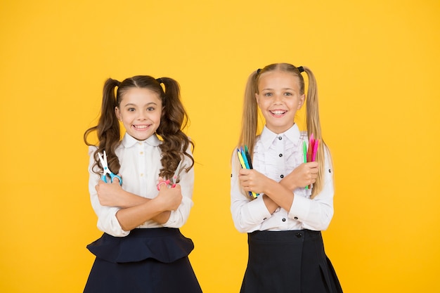 Inspireer uw kinderen om creatief te worden. Gelukkige kinderen met schaar en markeringen. Mijn lieve kinderen lachend met handige tools op gele achtergrond. Kunst- en knutselactiviteiten voor kleine kinderen.