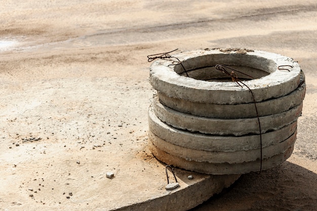 Foto installatie van betonnen rioolputten in de grond op de bouwplaats. het gebruik van ringen van gewapend beton voor beerputten, overloop septic tanks. verbetering van putten en regenwaterafvoer.