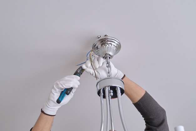 Installation ceiling lamp, hands of male electrician fixing chandelier with use of professional tools