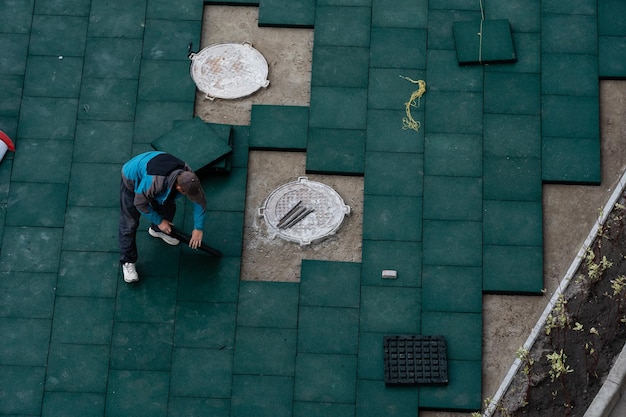 Installazione di pavimentazione elastica in gomma sintetica epdm su superficie asfaltata esistente come pavimentazione di un parco giochi. i tappetini di sicurezza in epdm riducono il rischio di lesioni causate da cadute su campi da gioco e impianti sportivi.