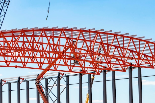 Installation of metal trusses and frame during the construction of an industrial building or factory The work of installers during the installation of the roof Construction of a large frame shop