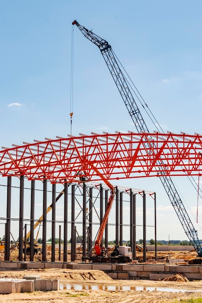 Installation of metal trusses and frame during the construction\
of an industrial building or factory the work of installers during\
the installation of the roof construction of a large frame\
shop