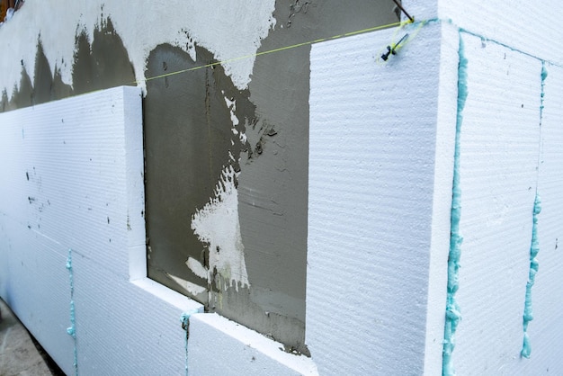 Фото Монтаж листов пенополистирола на стене фасада дома для тепловой защиты.