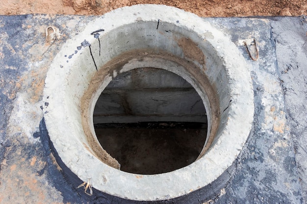 Installation of a reinforced concrete well for water supply and sewerage at the construction site Well rings with cast iron hatch and construction tool