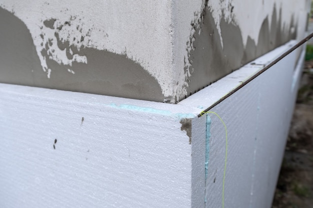 Installation of styrofoam insulation sheets on house facade wall for thermal protection.