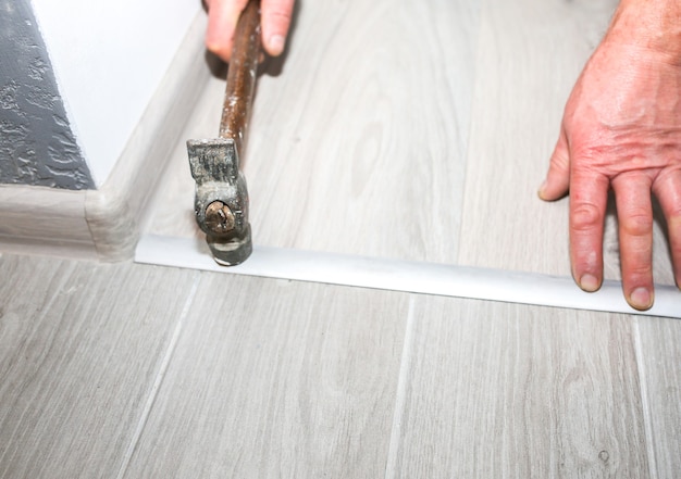 Installation of threshold indoors. renovation works in the
flat. man with a hammer.