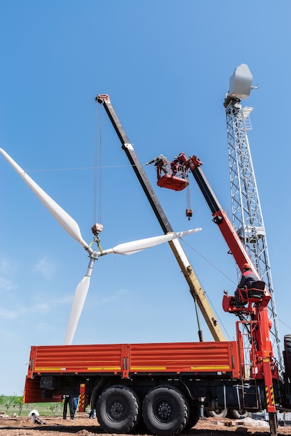 Photo installers use truck crane and aerial platform to raise wind turbine rotor