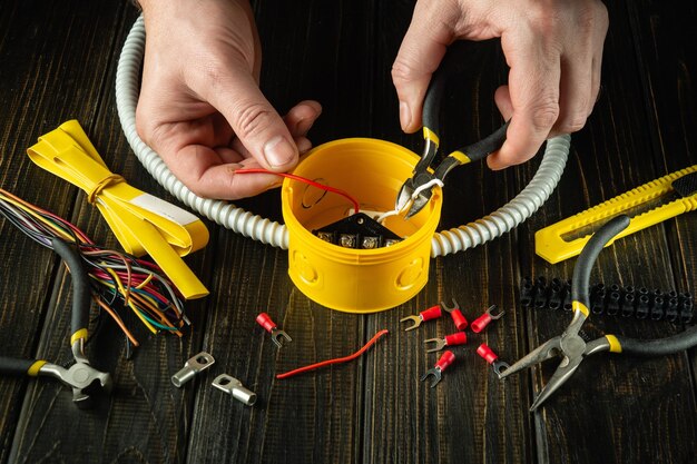 写真 黄色の接続箱にケーブルまたはワイヤを取り付ける 作業中のマスター電気技師 電気機器の設置と修理のアイデア