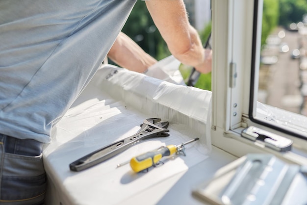 Installing an air conditioner in an apartment office closeup of an engineer installer's hands working with an outdoor unit male technician repairing with tools