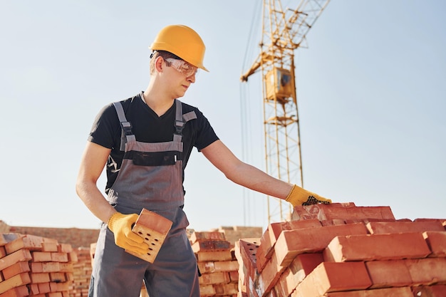 Installing brick wall Construction worker in uniform and safety equipment have job on building