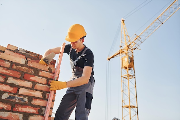 Installing brick wall Construction worker in uniform and safety equipment have job on building