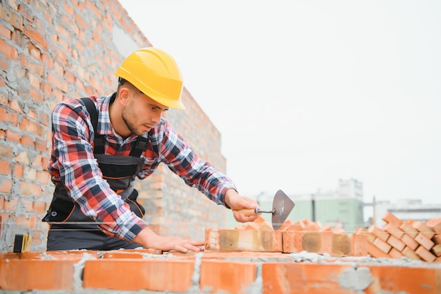 Installing brick wall Construction worker in uniform and safety equipment have job on building