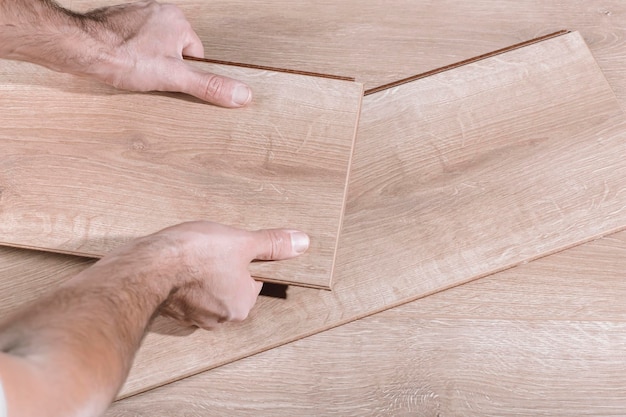 Foto l'installazione di pavimenti in laminato in una stanza o in un ufficio tavole di parquet in legno nelle mani di un lavoratore cost...