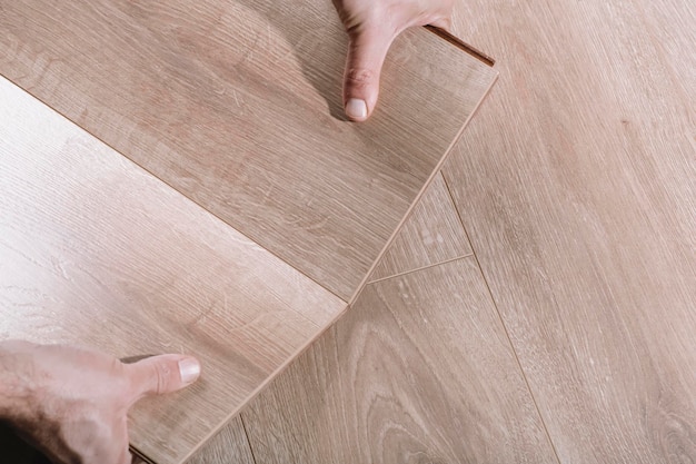 Installing laminate flooring in a room or office wooden parquet boards in the hands of a worker