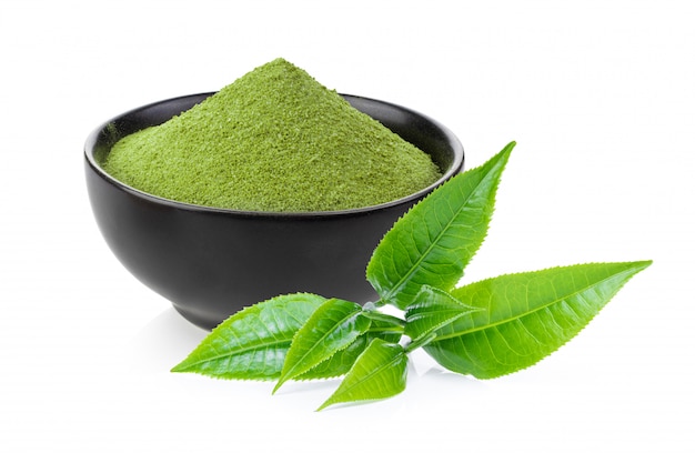 Tè verde istantaneo di matcha in ciotola e foglia nere su bianco