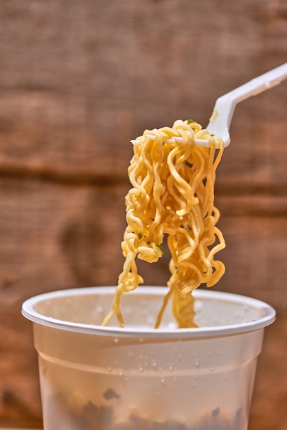 Instant noodle, asian fast food, noodle cup on wooden background.