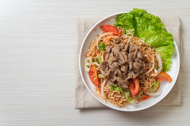 instant noodle spicy salad with pork on white plate - Asian food style