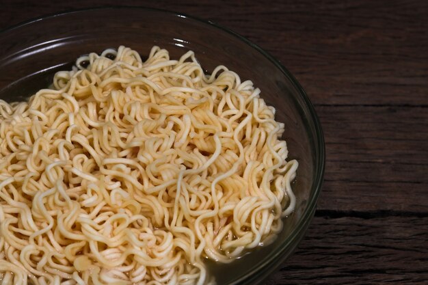 Instant noodles in bowl on wooden background.