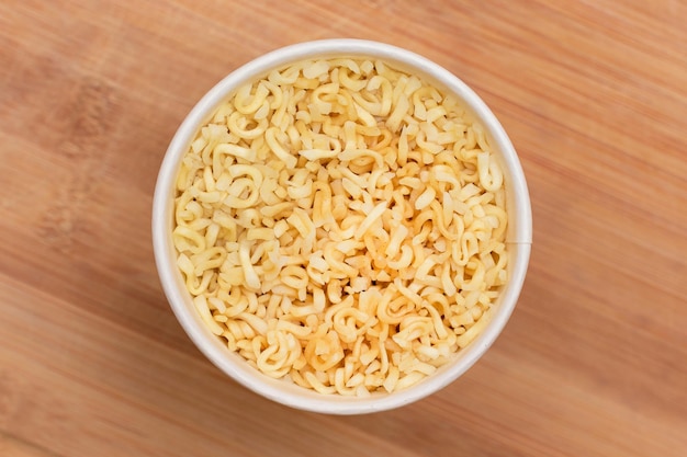 Instant noodles in disposable cup on wooden background