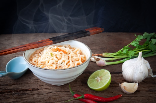 Photo instant noodles and ingredients, lime, garlic, chili and onion on wooden table