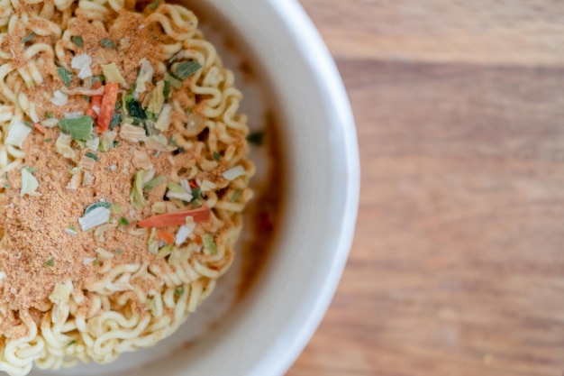 Instant noodles met smaakmakers op een houten achtergrond bovenaanzicht