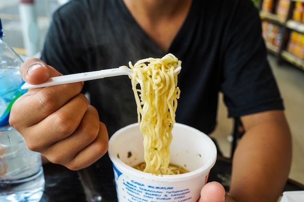 Instant noodles noedelsoep in een kopje jongens handvoeding klaar om noedels te eten