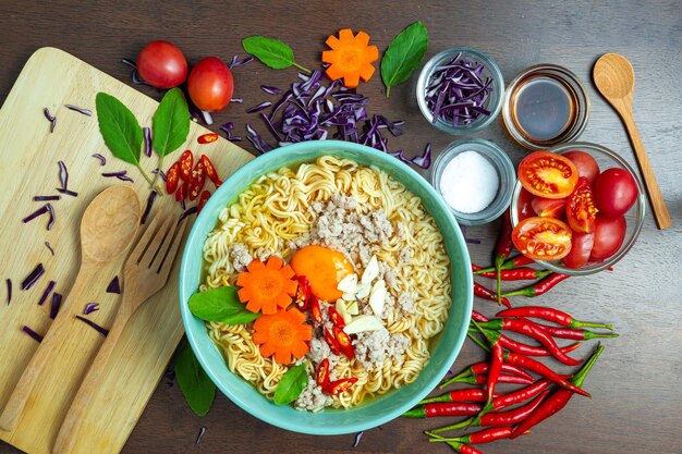 Instant noodles with fresh vegetables on wood background fastfood