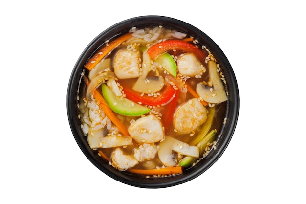 Foto instant soep, noedels wok, met groenten, kruiden en sesam. in een zwarte ronde plaat.