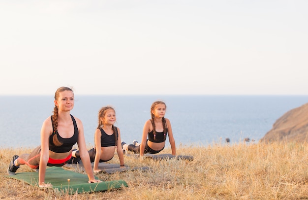 Instructeur traint yoga-kinderen in de bergen aan de oceaan.