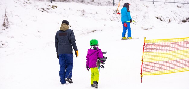 Instructeurs leren een kind op een sneeuwhelling snowboarden