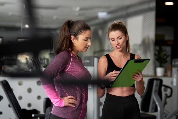 Foto istruttore che discute con una donna in palestra