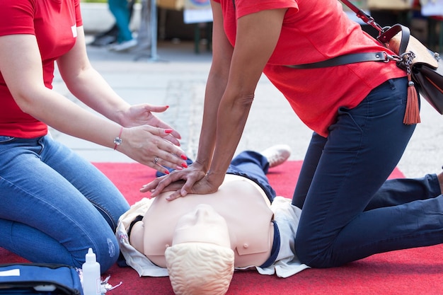 Photo instructor explaining rescue worker while giving cpr to mannequin