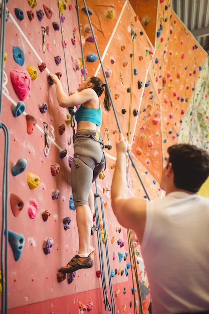 Instructor guiding woman on rock climbing wall