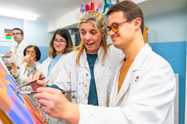 Instructor helping a man with down syndrome to paint