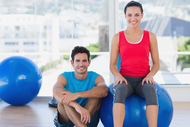 Instructor and smiling woman with exercise ball at gym