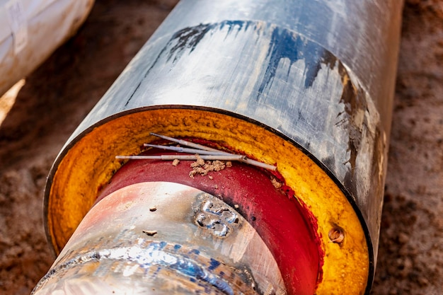 Insulated pipe Large metal pipes with a plastic sheath laid in a trench Welding pipes together in a pit at a construction site