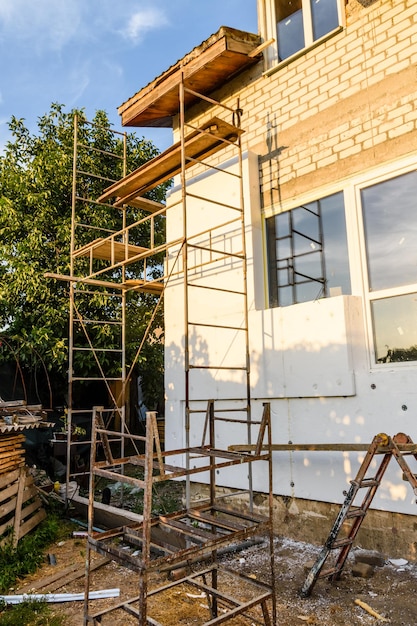 Insulation of the house with styrofoam. Scaffold on building