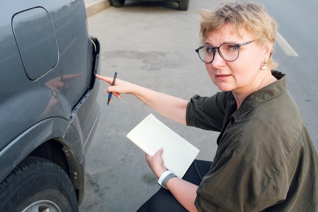 La donna di mezza età dell'agente assicurativo conduce l'ispezione pre-assicurativa dell'auto