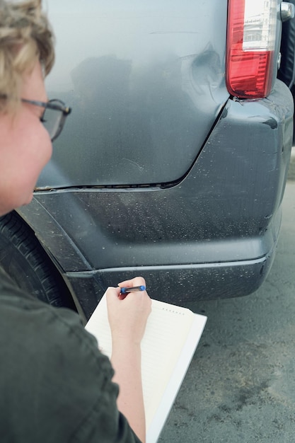 Insurance agent middleaged woman conducts preinsurance inspection of car