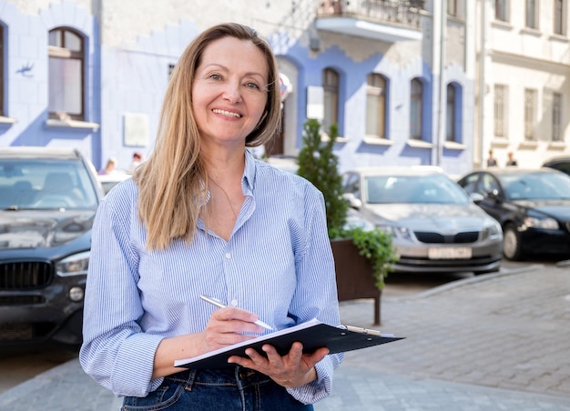 Insurance agent woman smilingly looks into the camera on the background of cars