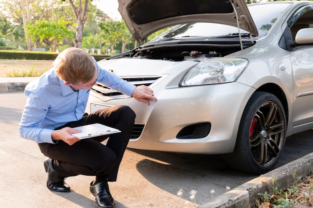 Photo insurance agent writing document on clipboard examining car after accident, insurance concept