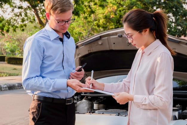 Photo insurance agent writing document on clipboard examining car after accident, insurance concept